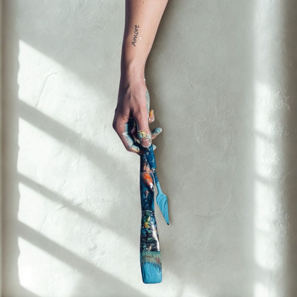 Paint-covered hand holding a brush in Sabine Runge’s contemporary art studio.
